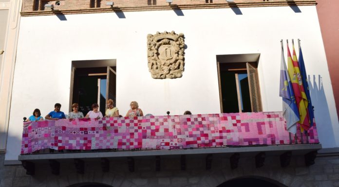 Voluntarias de la AECC engalanado del rosa reivindicativo el balcón de la casa consistorial de Graus (Foto: Angel Gayúbar)