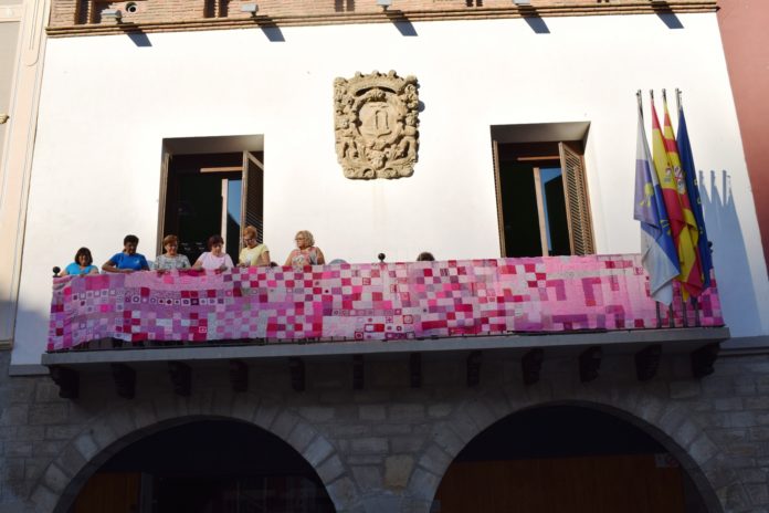Voluntarias de la AECC engalanado del rosa reivindicativo el balcón de la casa consistorial de Graus (Foto: Angel Gayúbar)