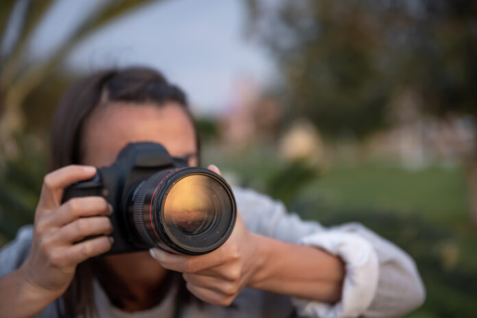 Close up of a girl makes a photo on a professional camera.